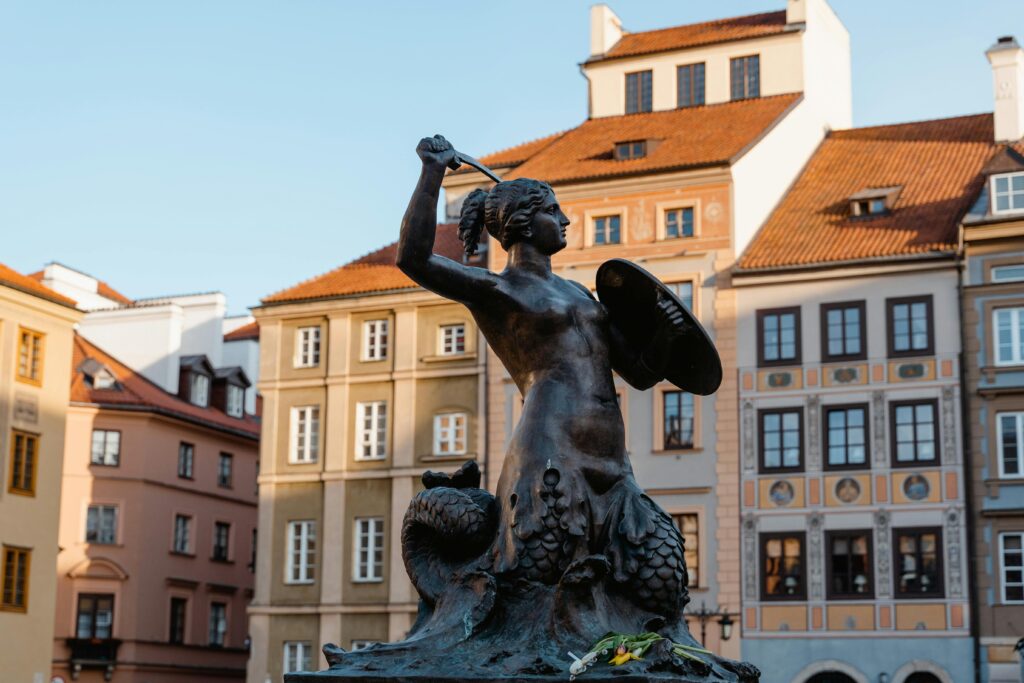 Polaco para hispanohablantes The iconic Syrenka statue in Warsaw's Old Town, representing the city's emblem under daylight.